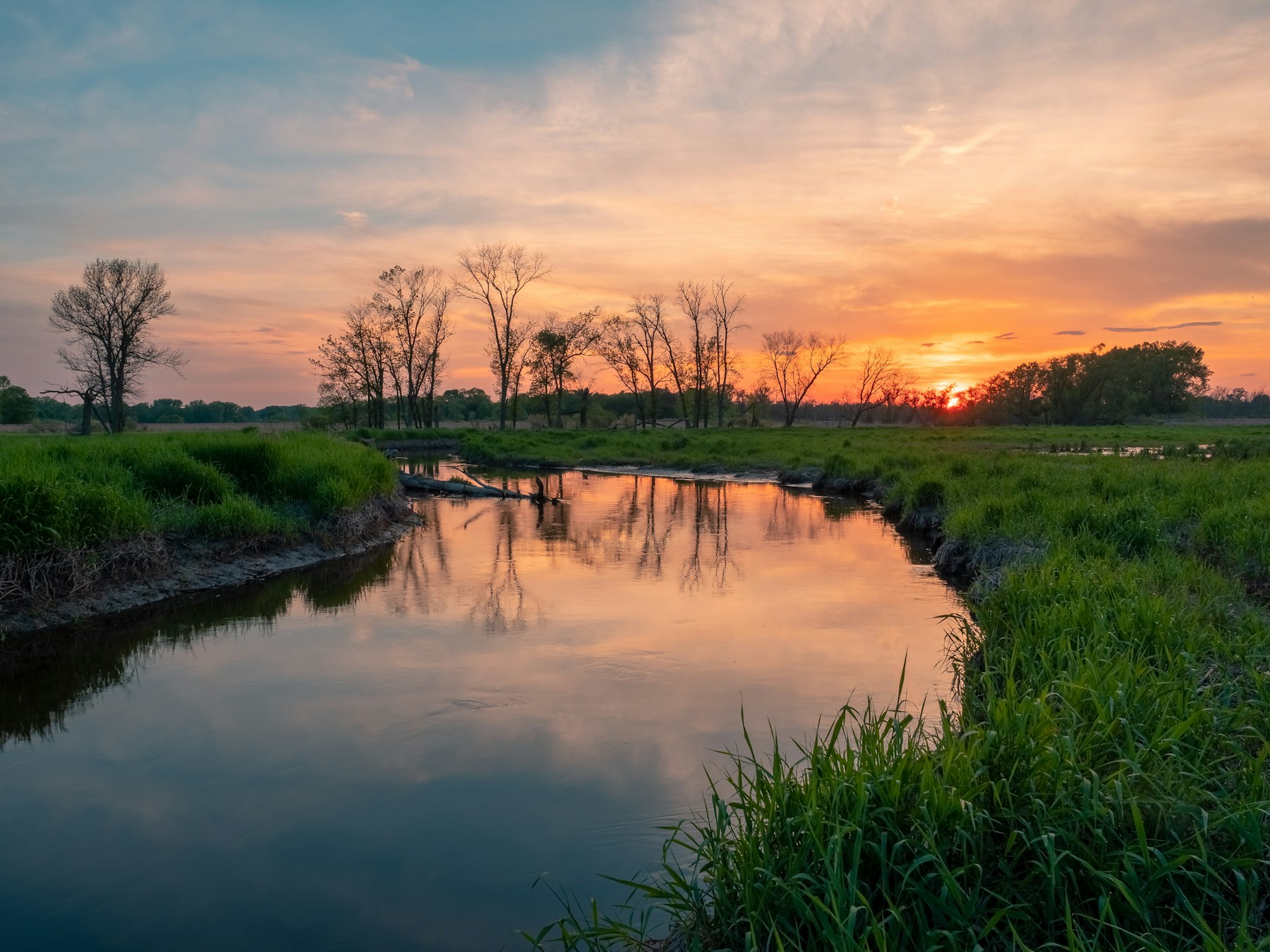 A quiet creek reflecting warm evening light after sunset